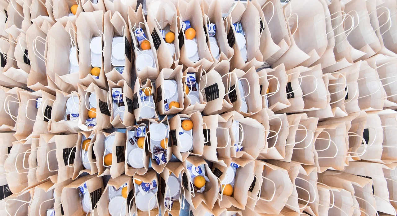 Vue du dessus de nombreux sacs en papier contenant des produits alimentaires et des oranges.